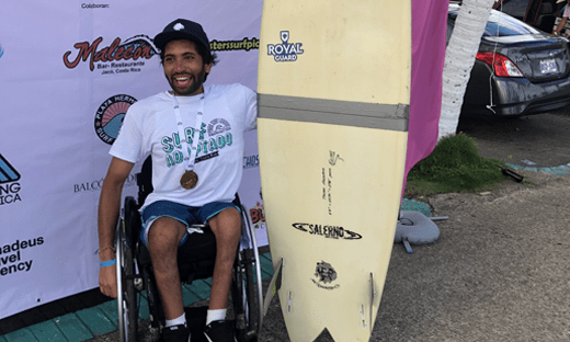 Man in a Wheelchair Holding a Surfboard
